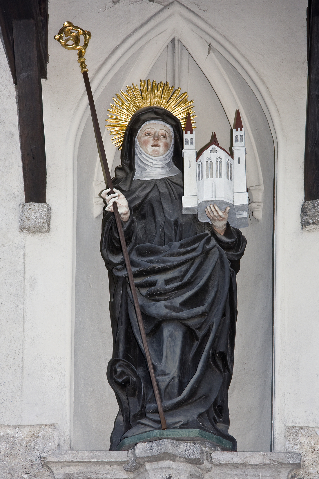 Die Statue  der heiligen Erentrudis wacht über einem Torbogen des Klosters der Nonnbergschwestern hoch über der Stadt Salzburg.  