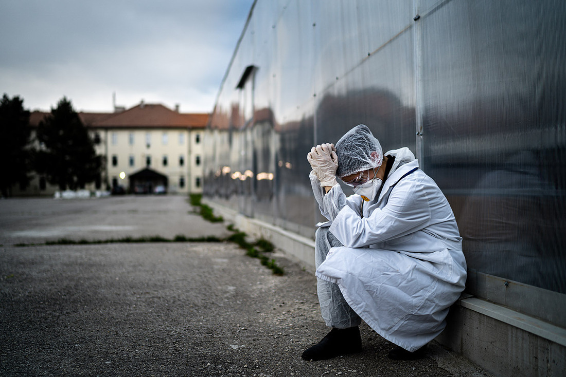 Frightened doctor for infectious diseases having mental nervous break down.Coronavirus COVID-19 exhausted physician in fear.Working in improvised medical facility isolation ward.Medical worker stress